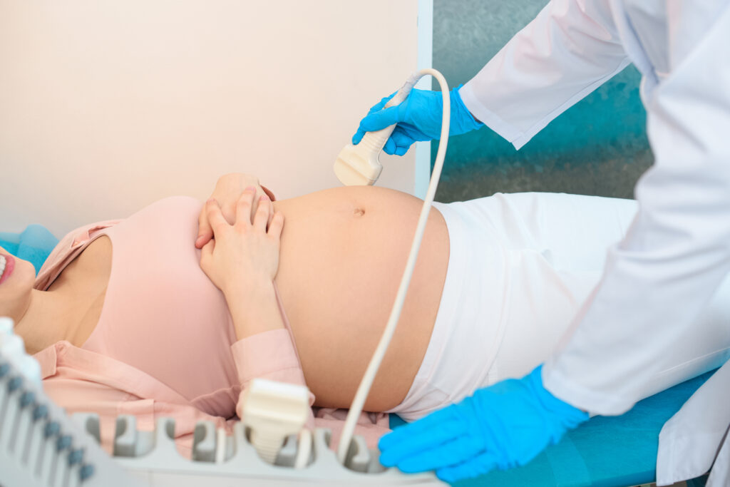 cropped shot of obstetrician gynecologist making of ultrasound examination pregnant woman
