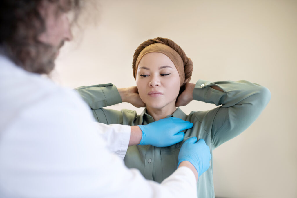 Examination. Dark-haired mammologist palping lymph nodes of his patient